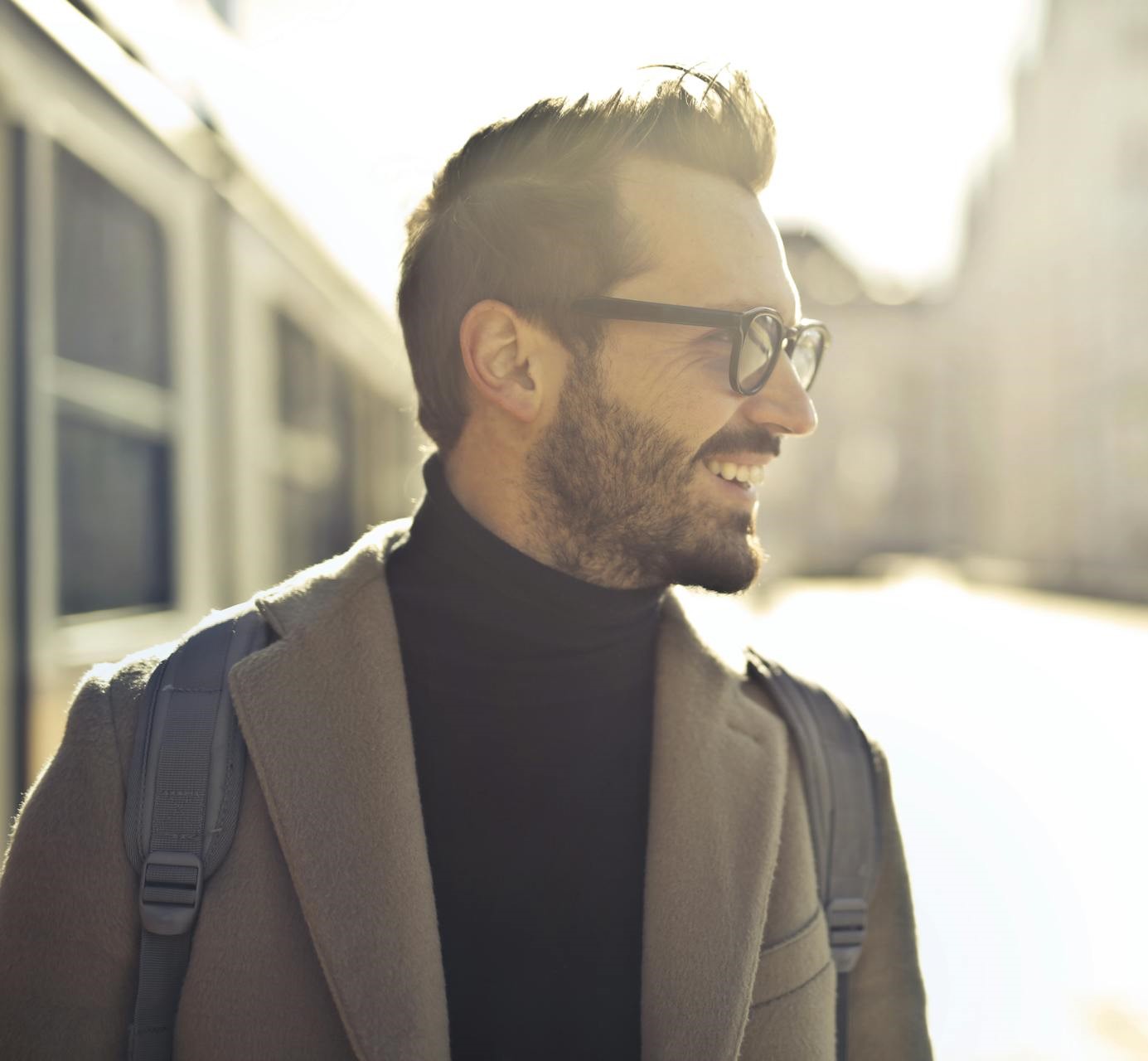 Young adult male smiling with glasses wearing a backpack